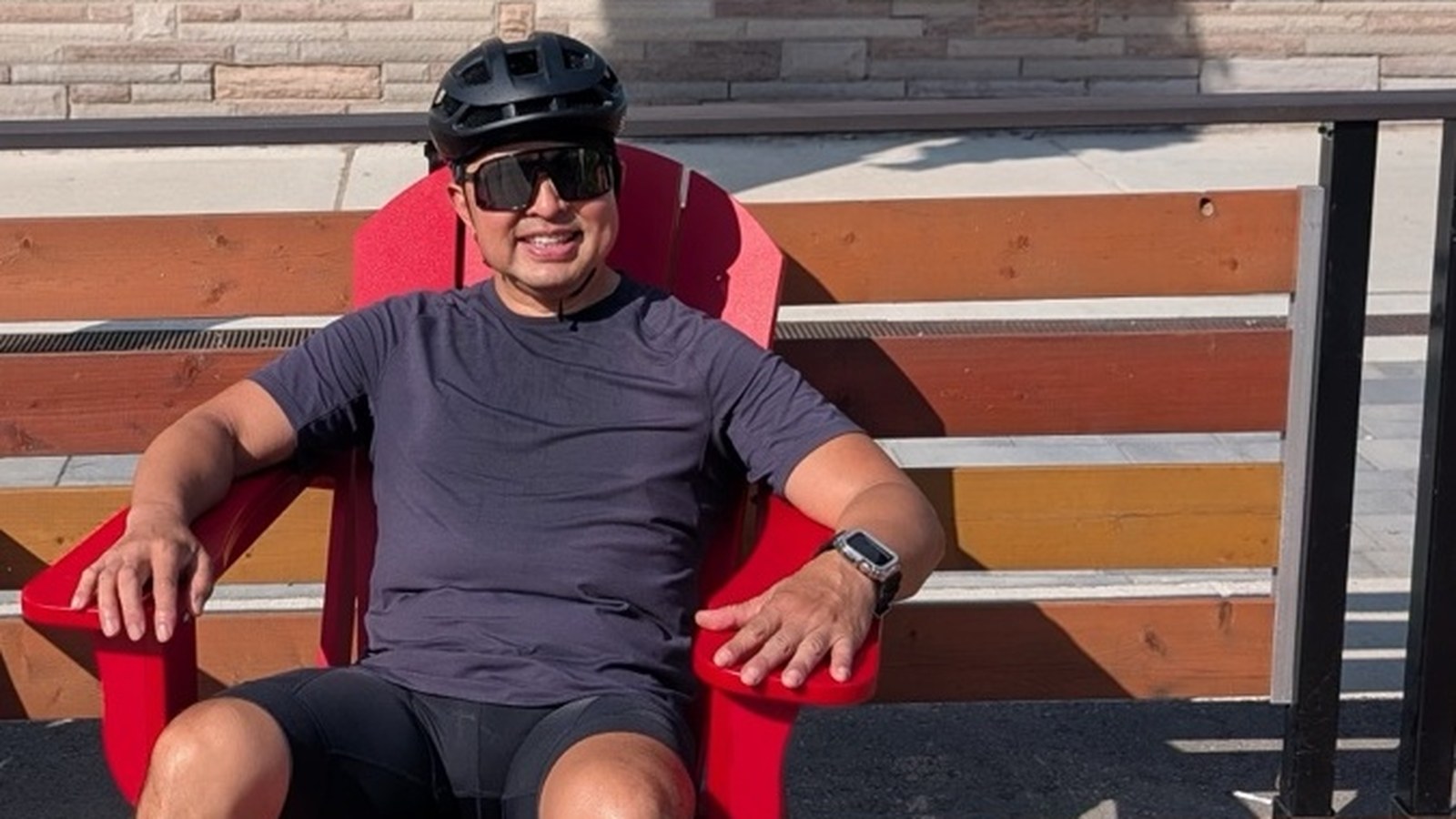 Eric Mallari relaxing in a red chair during a break from a summer cycling ride.